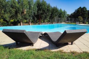two wicker chairs sitting in front of a swimming pool at Résidence de Filitosa - Le Torréen in Sollacaro