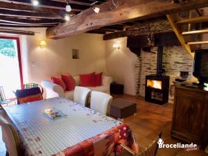 sala de estar con mesa y chimenea en Gîte Le Logis de l'Etang de l'Aune, en Iffendic