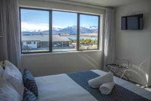 sypialnia z łóżkiem i dużym oknem w obiekcie Tekapo Luxury Apartments w mieście Lake Tekapo