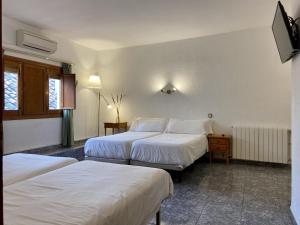 Una habitación de hotel con dos camas y un televisor. en El Mesón de Despeñaperros, en Santa Elena
