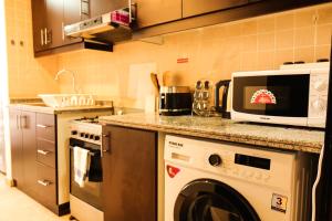 a kitchen with a washing machine and a microwave at SHH - Furnished Studio in Silicon Gates 1, Silicon Oasis in Dubai