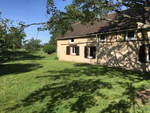 ein altes Haus mit einem großen Rasenplatz in der Unterkunft Gîte à l'orée de Grandchamp in Grandchamp