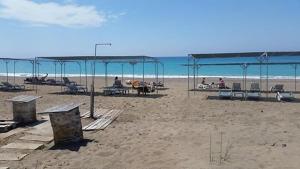 een strand met tafels en stoelen en de oceaan bij Hotel Schönberg in Kızılot