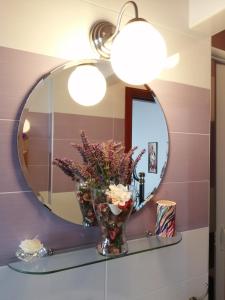 オリアストロ・チレントにあるTramonto Su Capriのバスルーム(鏡付)が備わります。棚に花瓶を用意しています。