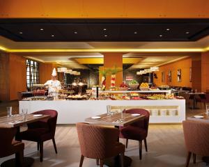 a restaurant with tables and a chef in the kitchen at Sunway Lagoon Hotel , formerly Sunway Clio Hotel in Kuala Lumpur