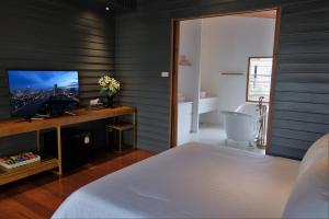 a bedroom with a bed and a tv and a tub at Vali Villa Bangkok in Bangkok