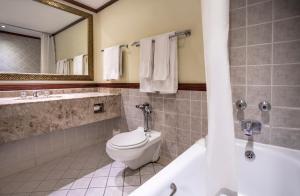 a bathroom with a toilet and a tub and a sink at Avani Gaborone Resort & Casino in Gaborone