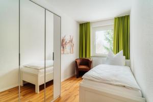 - une chambre avec un miroir, un lit et une chaise dans l'établissement Bode_Apartments, à Elend