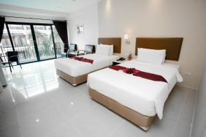 2 camas en una habitación de hotel con paredes blancas en Summer Tree Hotel, en Bangna