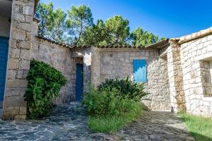 una casa de piedra con una puerta azul y árboles en Résidence de Filitosa - Le Torréen en Sollacaro