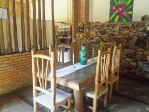 una mesa con sillas y un jarrón con flores. en Pousada das Bromélias, en Serra do Cipo