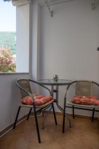 2 chaises et une table en verre dans une pièce dans l'établissement Apartman Zenta, à Petrovac na Moru