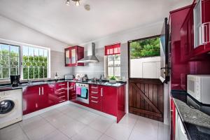 - une cuisine avec des placards rouges et un lave-linge dans l'établissement Buganvilia by Algarve Villa Holidays, à Guia