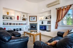 sala de estar con 2 sofás de cuero y TV en Villa Buganvilia, en Guia