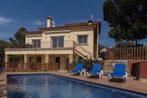 a house with two blue chairs and a swimming pool at La Llevantina Boutique Villa in Calonge
