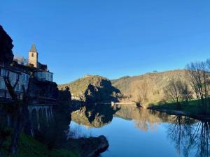 Blick auf einen Fluss mit einer Kirche auf einem Hügel in der Unterkunft Les Gîtes du Rocher et de la Boucle du Tarn in Ambialet
