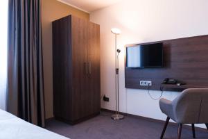 a hotel room with a cabinet and a tv at Steinberger Hof in Dietzenbach