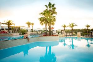 a person sitting on the edge of a swimming pool at ROBINSON AGADIR - All Inclusive in Agadir