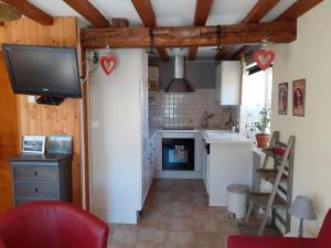 a kitchen with white cabinets and a tv on the wall at Gite du gros pommier in Saulxures