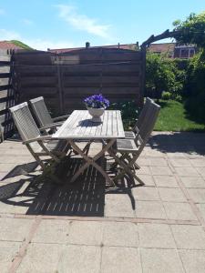 een houten picknicktafel met 2 stoelen en een vaas met bloemen bij Vakantiewoning 100m van het strand met 1 Slaapkamer in Westkapelle