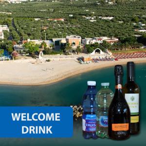 tres botellas de vino sentadas en una mesa junto a una playa en Apartments Villaggio Riccio, en Mattinata