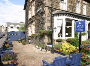 a sign in front of a house with blue benches at Adam Place Guest House in Windermere