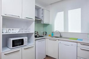 a white kitchen with white cabinets and a microwave at The Room Hotel & Apartments in Antalya