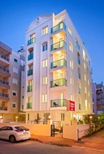 a white car parked in front of a tall building at The Room Hotel & Apartments in Antalya