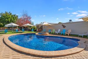 una gran piscina con sillas y sombrillas azules en Heritage Motor Inn Corowa, en Corowa