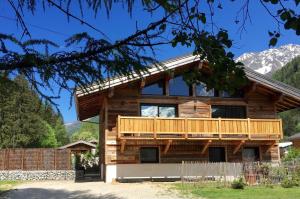 um chalé de madeira com um deque e montanhas ao fundo em Chalet le petit Nicolas, jacuzzi, vue Mont Blanc em Chamonix-Mont-Blanc