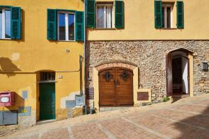 ein gelbes Gebäude mit einer Holztür und grünen Rollläden in der Unterkunft A casa di Giuly (Monolocale) in Ceriale