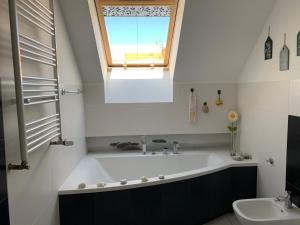baño con bañera grande y ventana en Silver Mazury Apartament en Giżycko