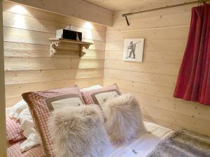 アヴォリアーズにあるChalet La Grange à Germaine - Propriétés Mont Amourの木製の壁のベッドルーム1室、毛皮の枕付きのベッド1台が備わります。