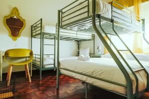 um quarto com 2 beliches e uma cadeira amarela em Help Yourself Hostels - Restelo em Lisboa