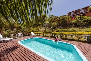 a person jumping into a swimming pool on a deck at Pousada Colina Verde in Garopaba