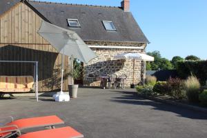une terrasse avec un parasol, une table et des chaises dans l'établissement Gîte La Loussaudrie, à Pontmain