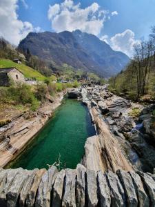 a river with green water and rocks and mountains at La Pergola in Avegno
