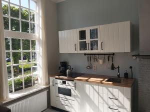 a kitchen with white cabinets and a stove and two windows at De Wachtkaemer in De olde banck in Stavoren
