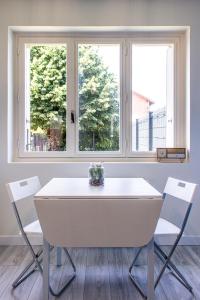 uma mesa branca e cadeiras num quarto com duas janelas em Maisonnette avec jardin, parc du chêne (tram T5) em Bron