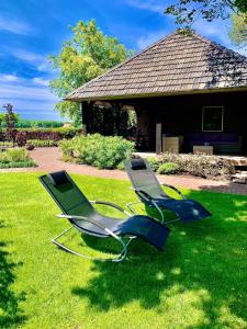 dwa krzesła siedzące w trawie przed domem w obiekcie De Slaaperij w mieście Wilbertoord