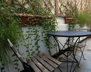 a table and a bench next to a wall with plants at Plaka's quality studio in Athens