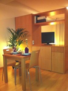 a dining room table with chairs and a television at Hotel-Apartamentos Tartesos in Las Rozas de Madrid