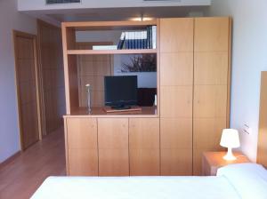a bedroom with a large wooden cabinet with a television at Hotel-Apartamentos Tartesos in Las Rozas de Madrid
