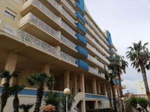 ein Gebäude mit Palmen davor in der Unterkunft Mar Azul Solo Familias Serviplaya in Casas Las Basas