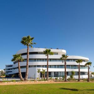 a building with palm trees in front of it at Longevity Health & Wellness Hotel - Adults Only in Alvor