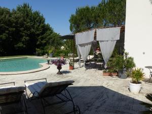 un patio con piscina, mesa y sillas en Les Anges, en LʼIsle-sur-la-Sorgue