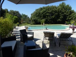 a patio with a table and chairs and a swimming pool at Les Anges in L'Isle-sur-la-Sorgue