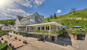 a large house with a hill in the background at Hotel Weinberg-Schlößchen in Oberheimbach