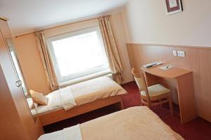 a room with two beds and a desk and a window at Guest House Pri Gondoli in Maribor