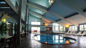 a pool in a building with chairs and tables at Pictured Rocks Inn and Suites in Munising